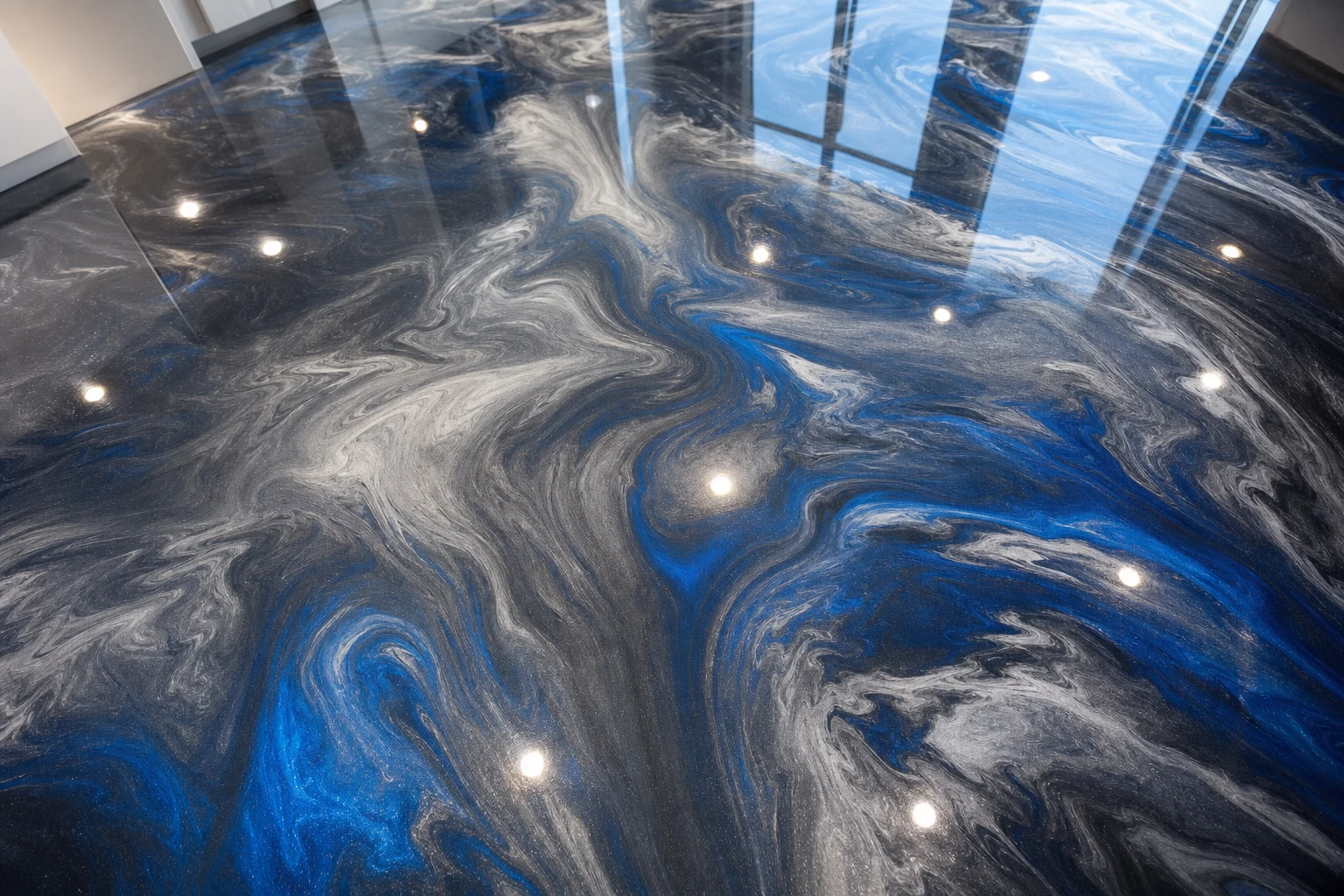 Overhead detail of a metallic epoxy floor with swirling charcoal, silver and cobalt-blue pigment under a glossy clear coat