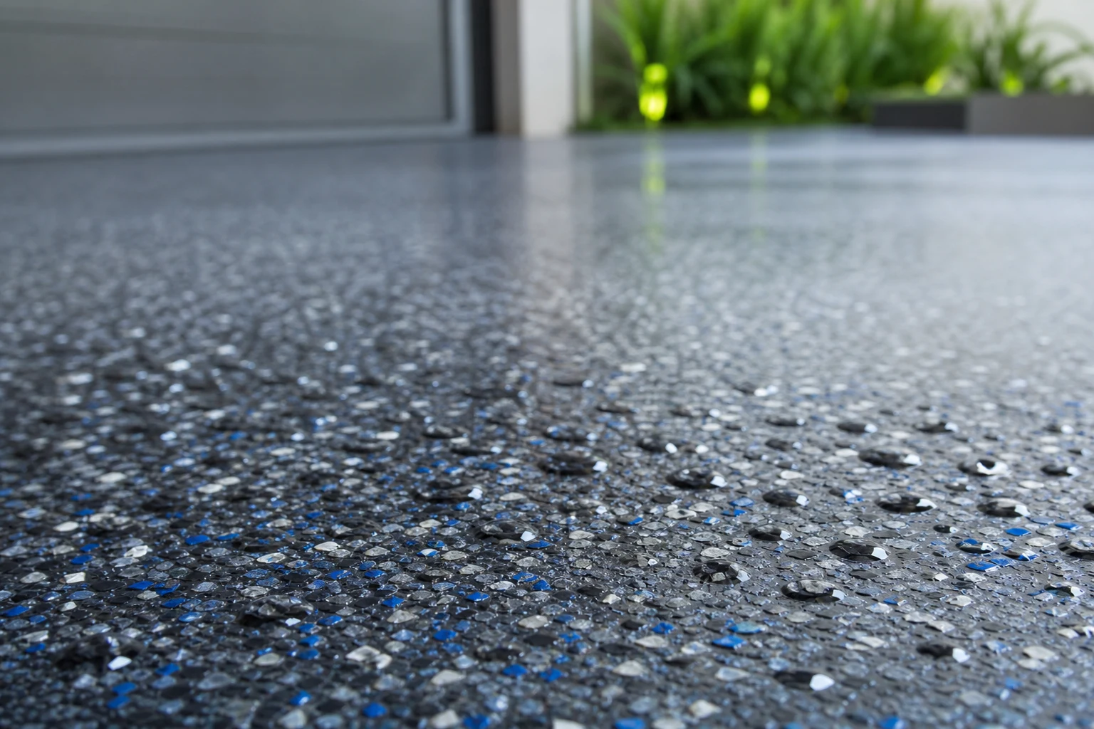 Macro detail of a textured anti-slip outdoor epoxy driveway surface with fine aggregate and rain droplets beading on it