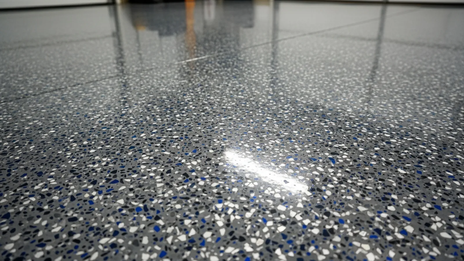Close-up of a mature charcoal and silver flake-chip epoxy floor still glossy after years of service, the speckled pattern disguising light traffic marks